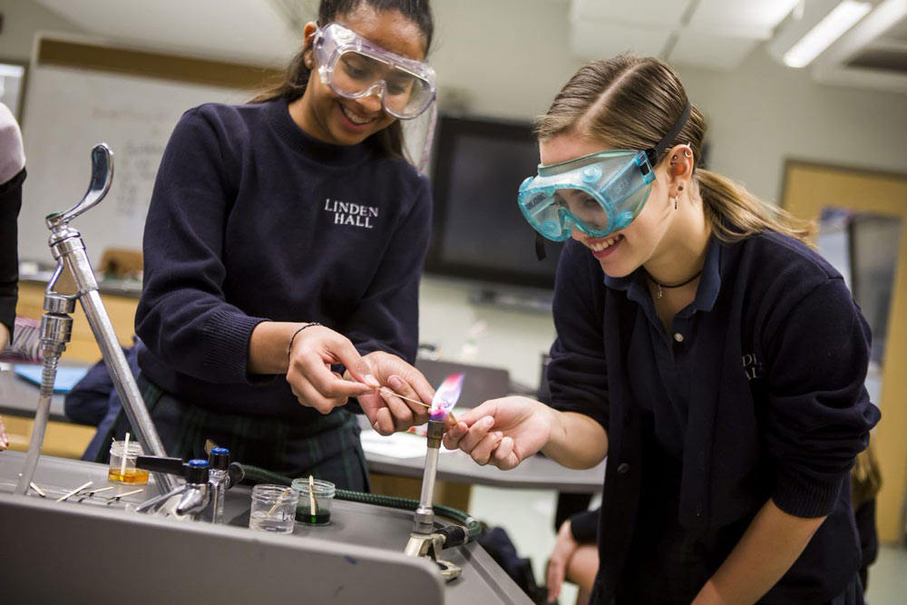 Smiling girls in science class with bunsen burner