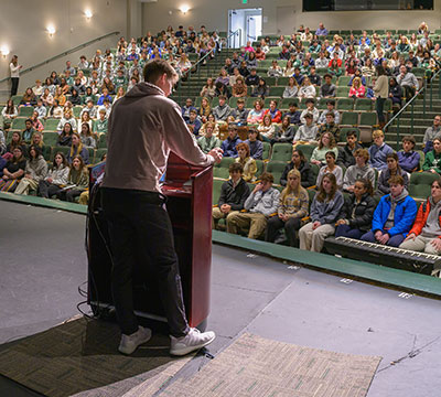 student giving a speech to a group at a podium